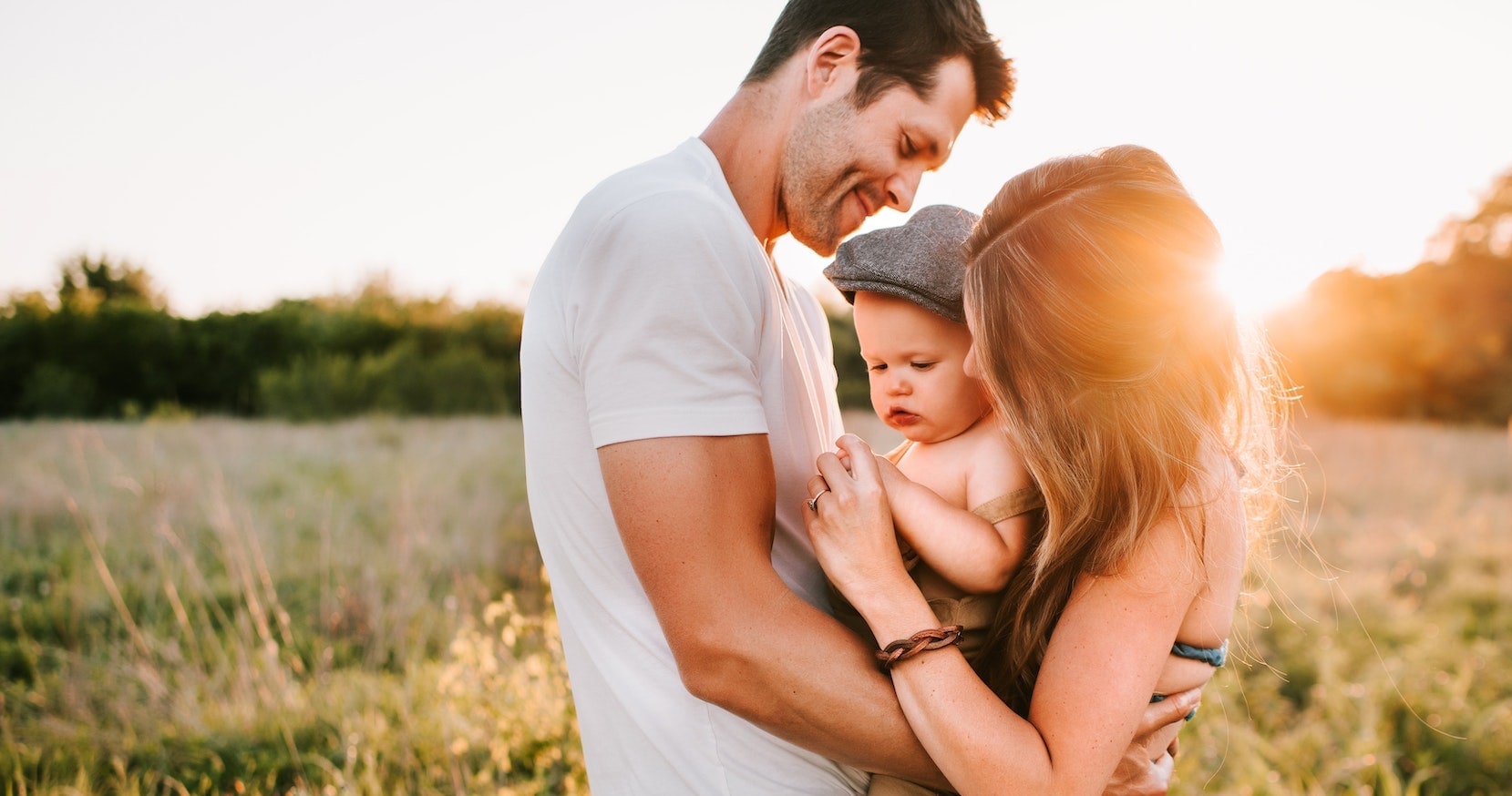 Ein junger Mann hält mit einer jungen Frau ein Kleinkind zwischen sich