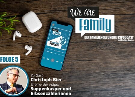 Auf einer Holzfläche steht ein Smartphone mit dem Cover des We-are-family-Podcast