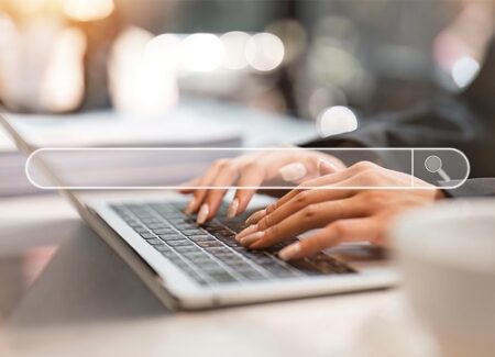 Eine weibliche Hand tippt auf der Tastatur eines Laptopes