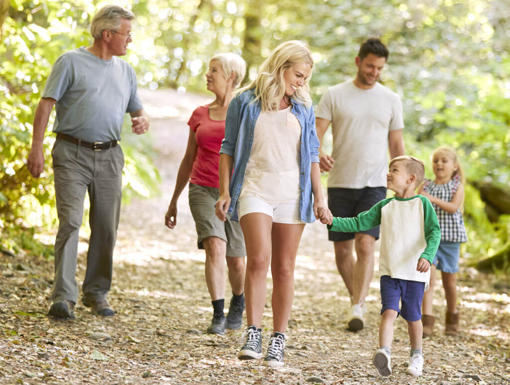 Eine Familie mit Eltern, Kindern und Großeltern spaziert durch einen Wald