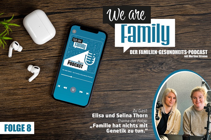 Auf einer Holzfläche steht ein Smartphone mit dem Cover des We-are-family-Podcast