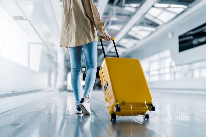 Eine Frau zieht auf einem Flughafen einen gelben Koffer hinter sich