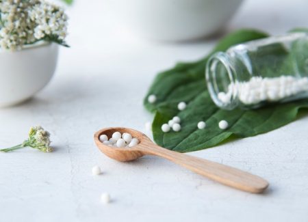 Homöopathische Kügelchen in einem Holzlöffel