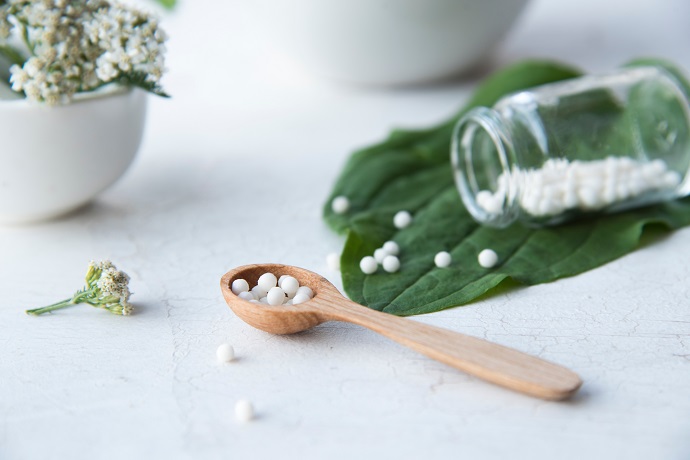 Homöopathische Kügelchen in einem Holzlöffel