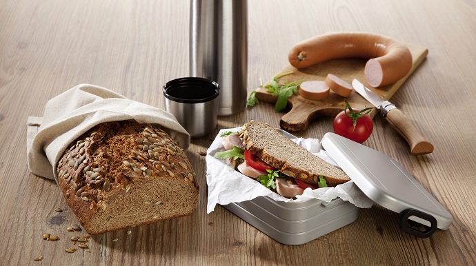 Das IKK Brot ist zusammen als belegtes Pausenbrot, einer Fleischwurst und Thermoskanne zu sehen