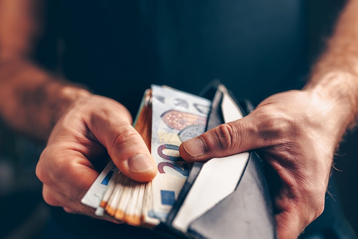 Ein Mann holt einen Bündel Geldscheine aus seiner Geldbörse
