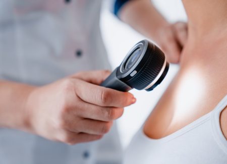 Mit einer Lupe wird die Haut einer Patientin untersucht