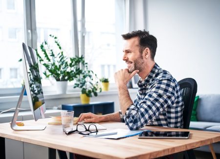 Ein Arbeitnehmer sitzt vor seinem Bildschirm und Schreibtisch