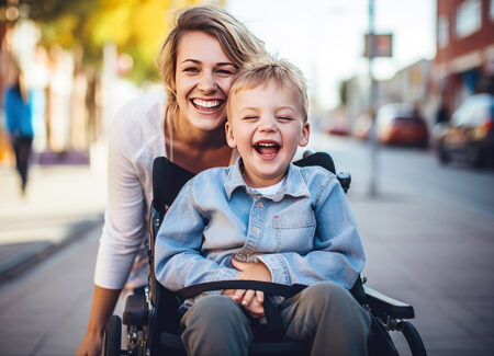 Mutter mit ihrem Sohn im Rollstuhl. Beide lachen fröhlich.