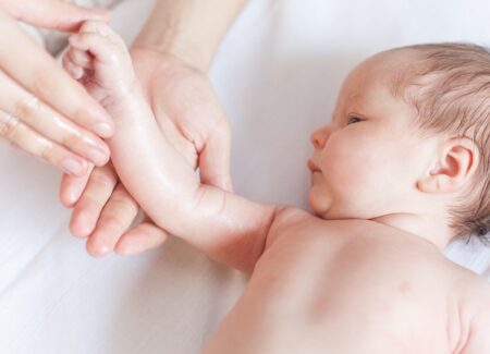Eine Frau massiert die Hand eines Babys