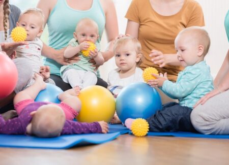 Mütter in einer Gruppe spielen zusammen mit ihren Babys und Bällen
