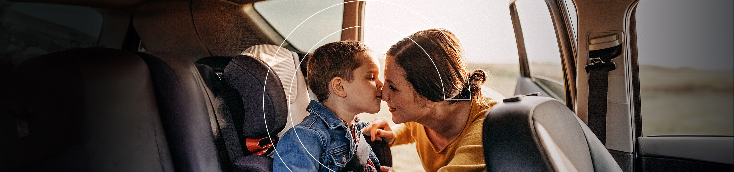 Ein Junge im Auto gibt seiner Mutter einen Kuss auf die Nase