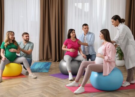 Schwangere Frauen sitzen in einem Geburtsvorbereitungskurs auf einem großen Medizinball