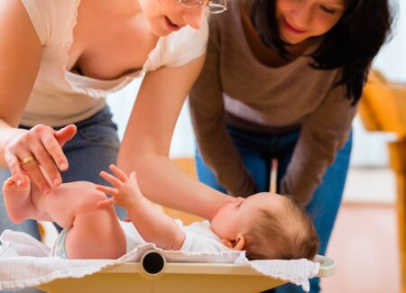 Eine Hebamme betrachtet mit der Mutter zusammen ein Baby