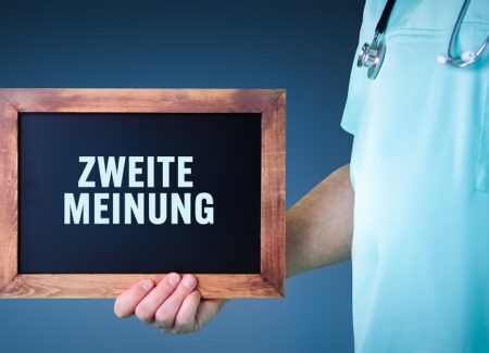 Ein Mann hält ein Schild in der Hand. Auf dem Schild steht Zweite Meinung