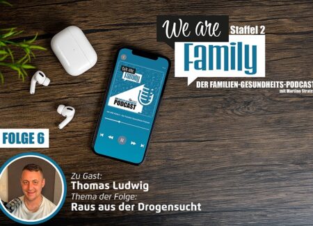 Auf einer Holzfläche steht ein Smartphone mit dem Cover des We-are-family-Podcasts