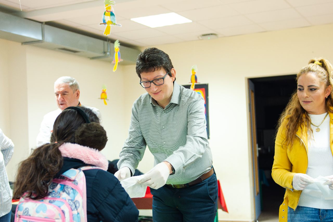 IKK-Südwest-Vorstand Prof. Dr. Jörg Loth reicht einem Grundschulkind ein Tütchen.