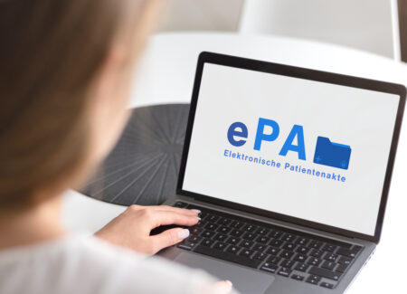 Eine Person tippt auf einem Laptop, auf dessen Bildschirm die Aufschrift ePA – Elektronische Patientenakte zu sehen ist.